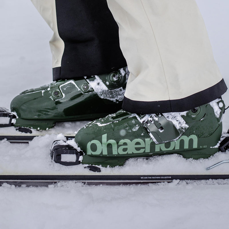 Skier standing with faction skis on and green freeride and touring ski boots phaenom fr 110