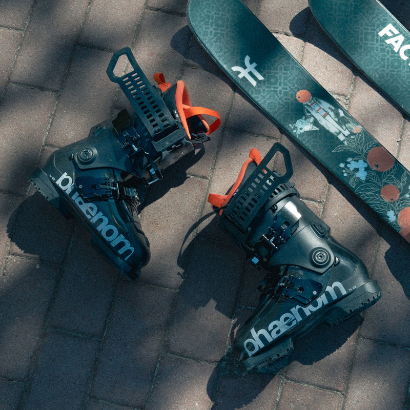Phaenom fs 02 130 freestyle and allmountain ski boots on ground next to Faction skis